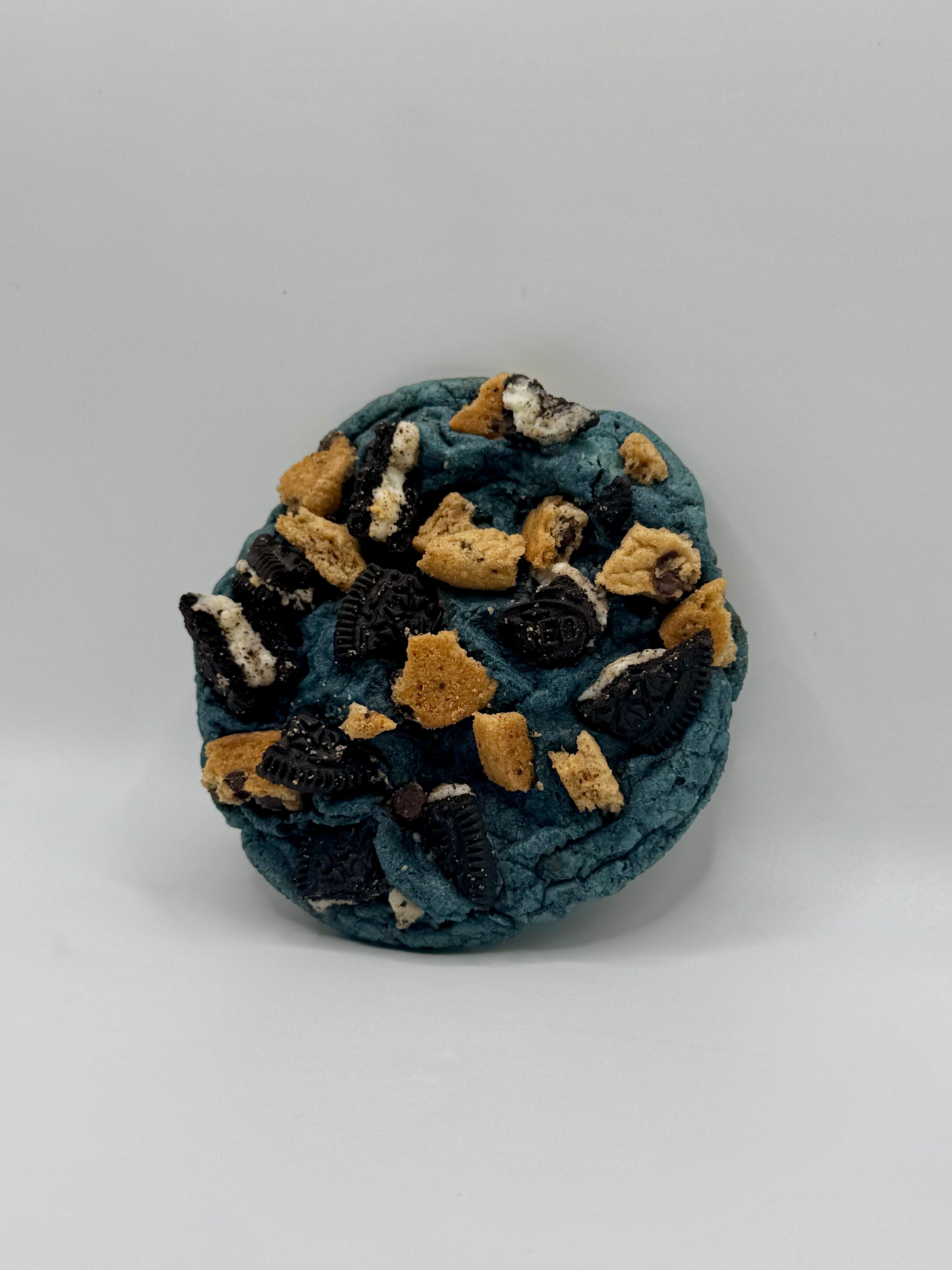 Round blue cookie with Oreo and Chips Ahoy Cookie Chunks Inside on a white background