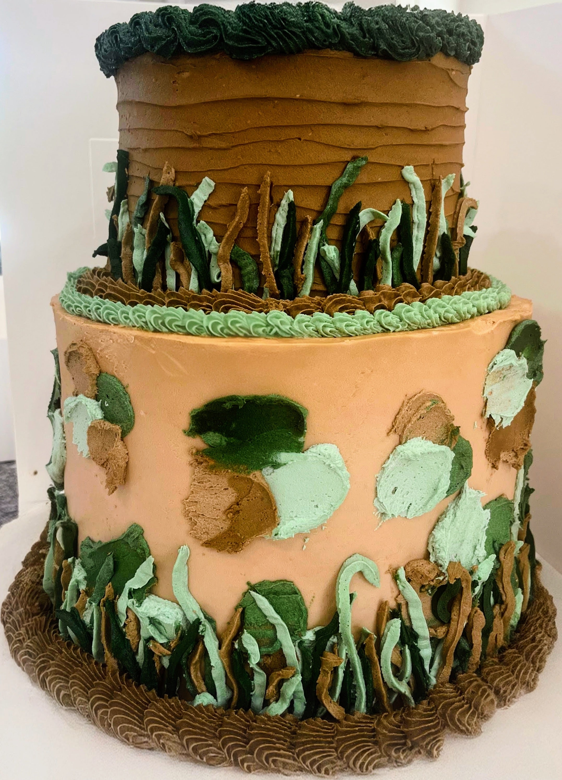 Three-tiered cake with a natural landscape design on a white background