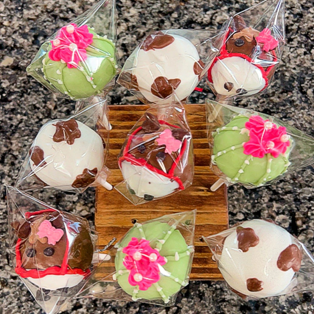 Decorative cookies shaped like horses and cacti in clear packaging on a wooden board.