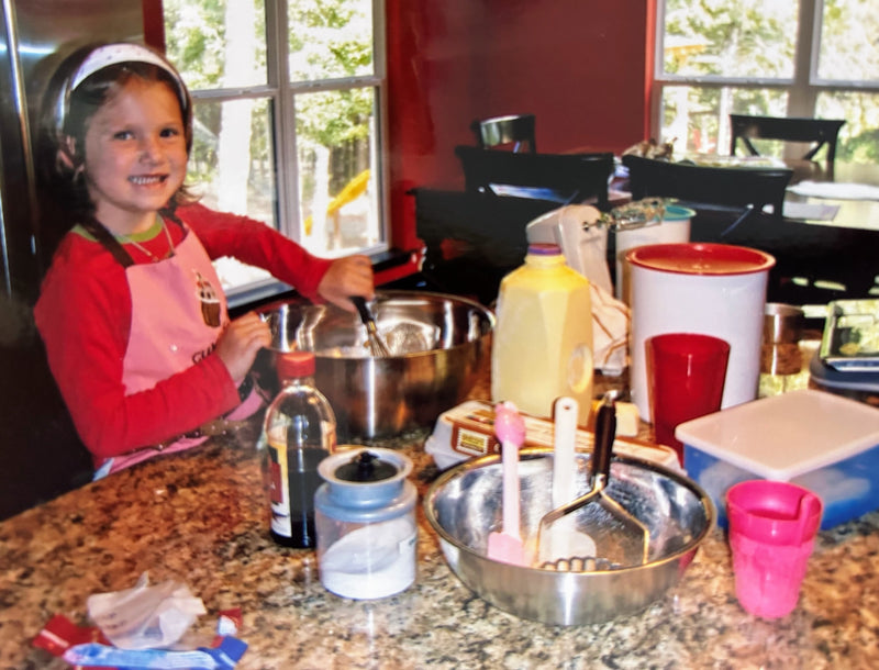 Child in a kitchen with cooking utensils and ingredients on a counter