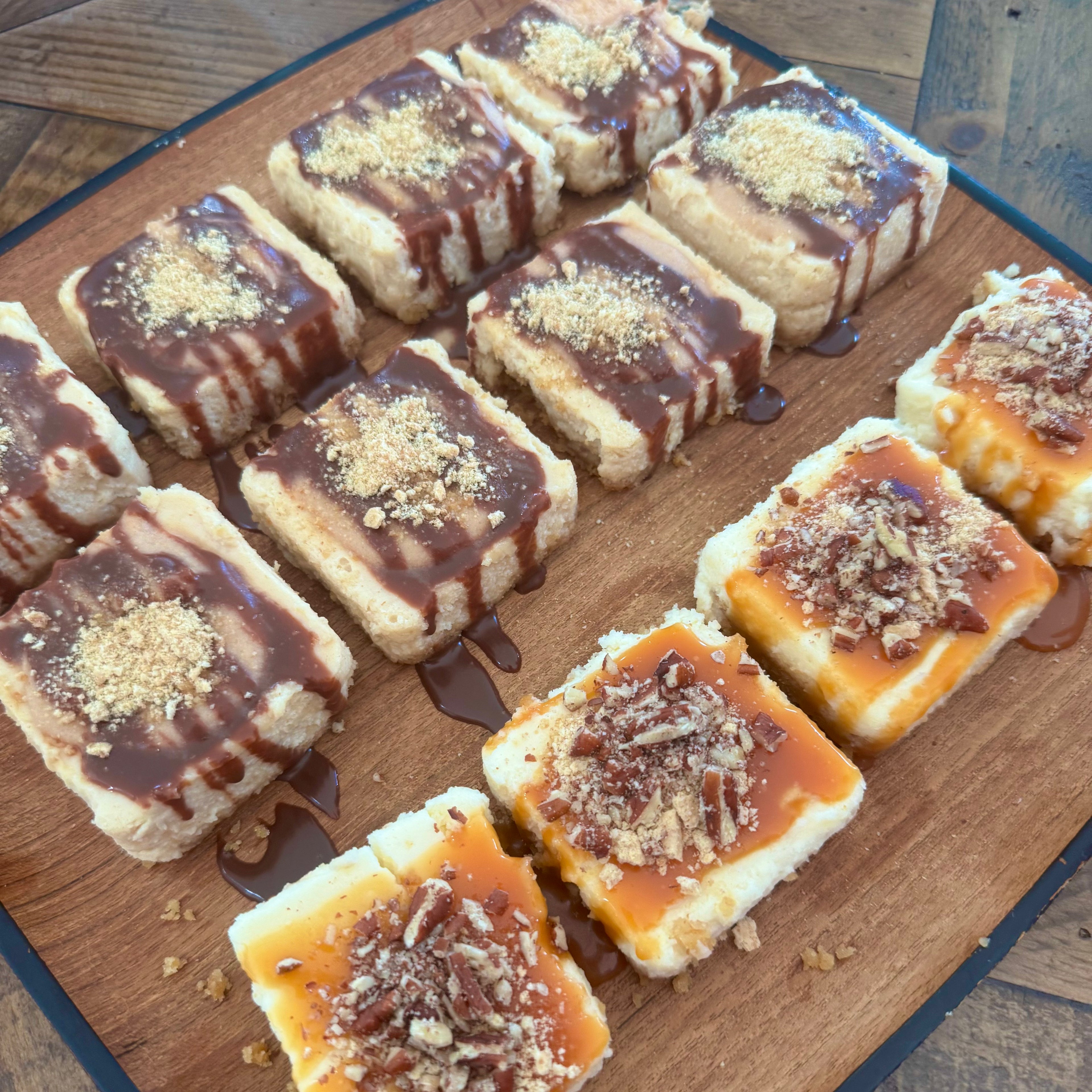 Mini square peanut butter cheesecakes with chocolate drizzle and mini square turtle cheesecakes with pecans and caramel drizzle. 