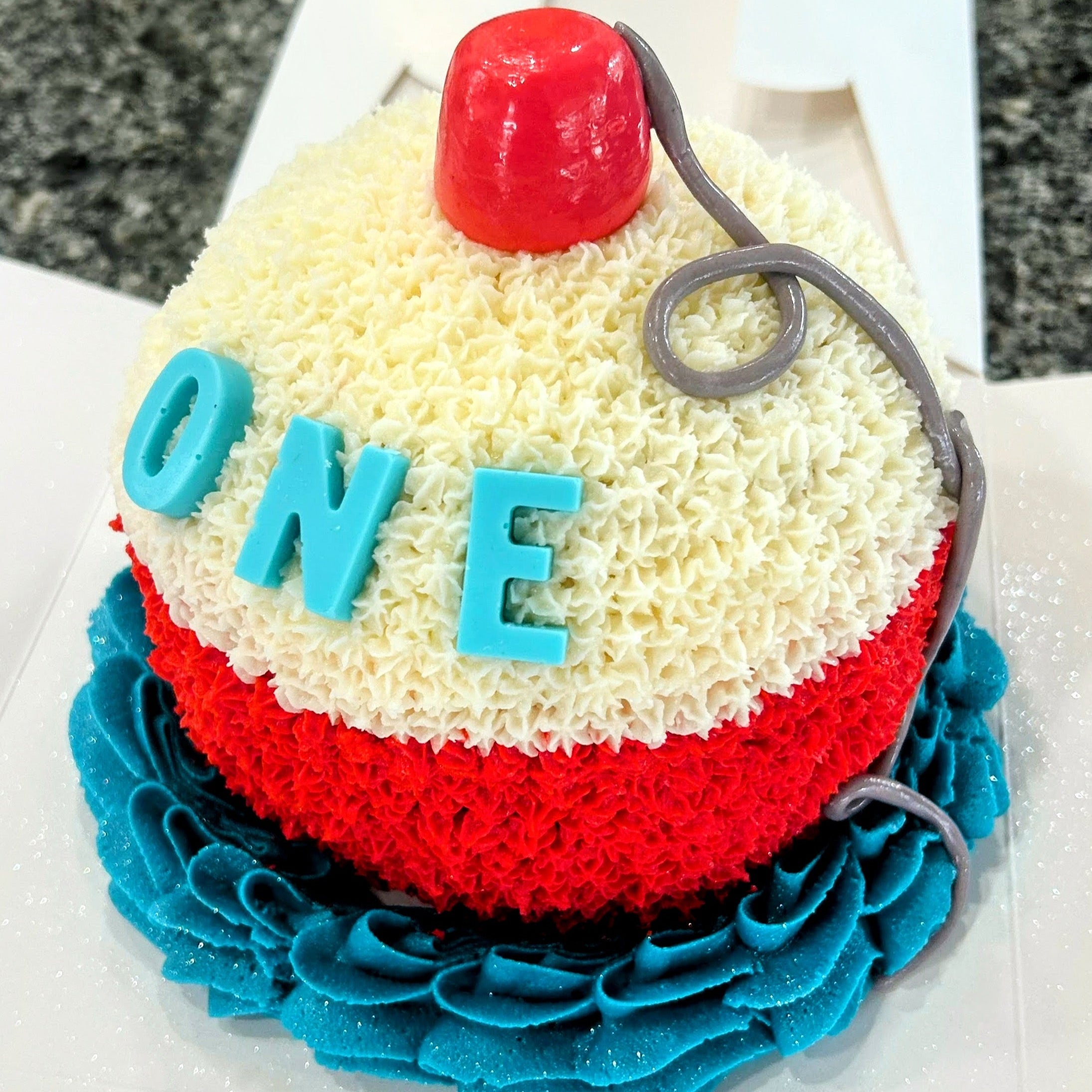 Birthday cake with red, white, and blue colors and the word 'ONE' on top.