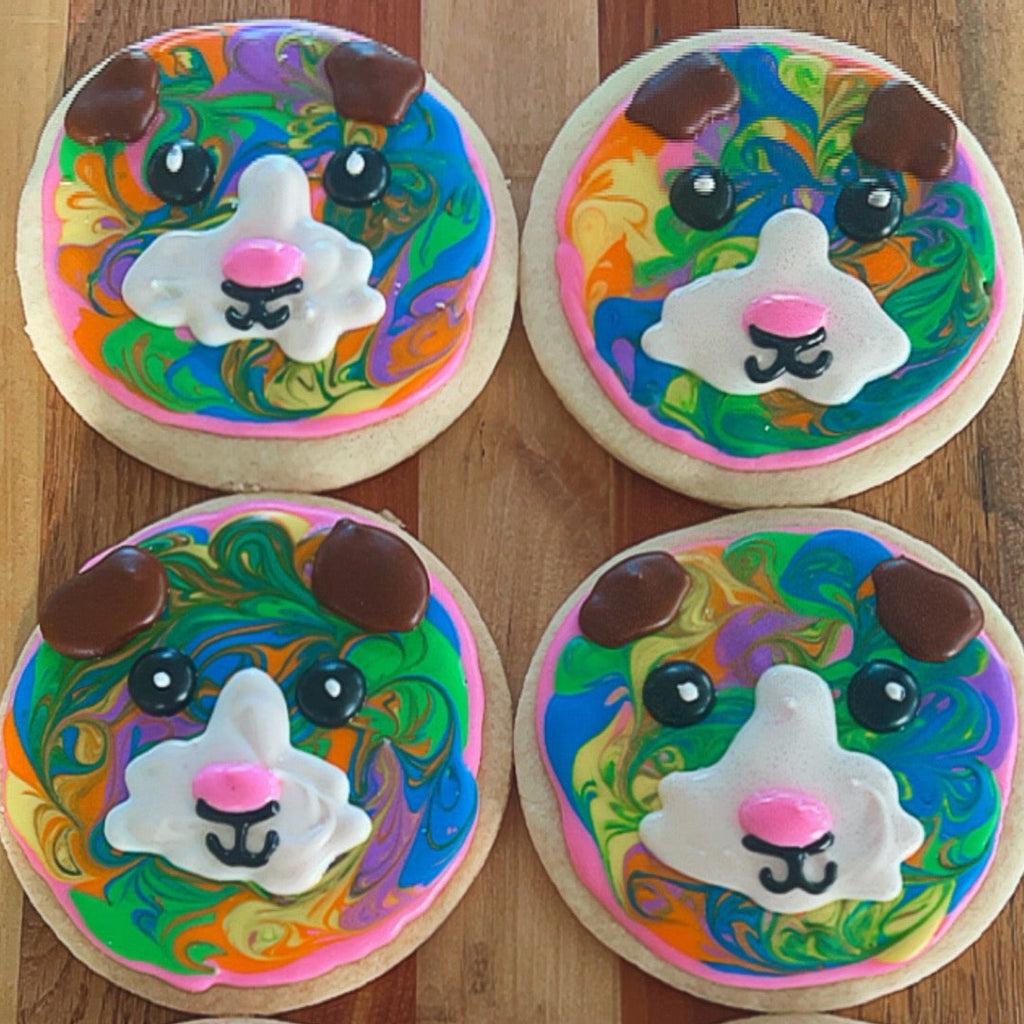 Four cookies decorated with colorful animal faces on a wooden surface