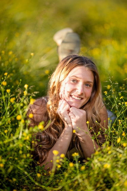 Woman lying in a field of yellow flowers with a blurred background