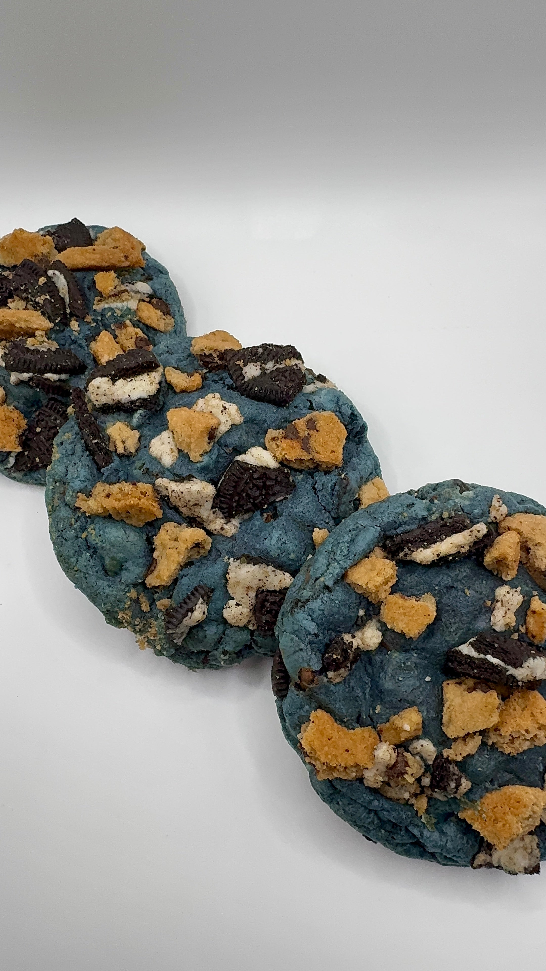 Round blue cookies with Oreo and Chips Ahoy Cookie Chunks Inside on a white background