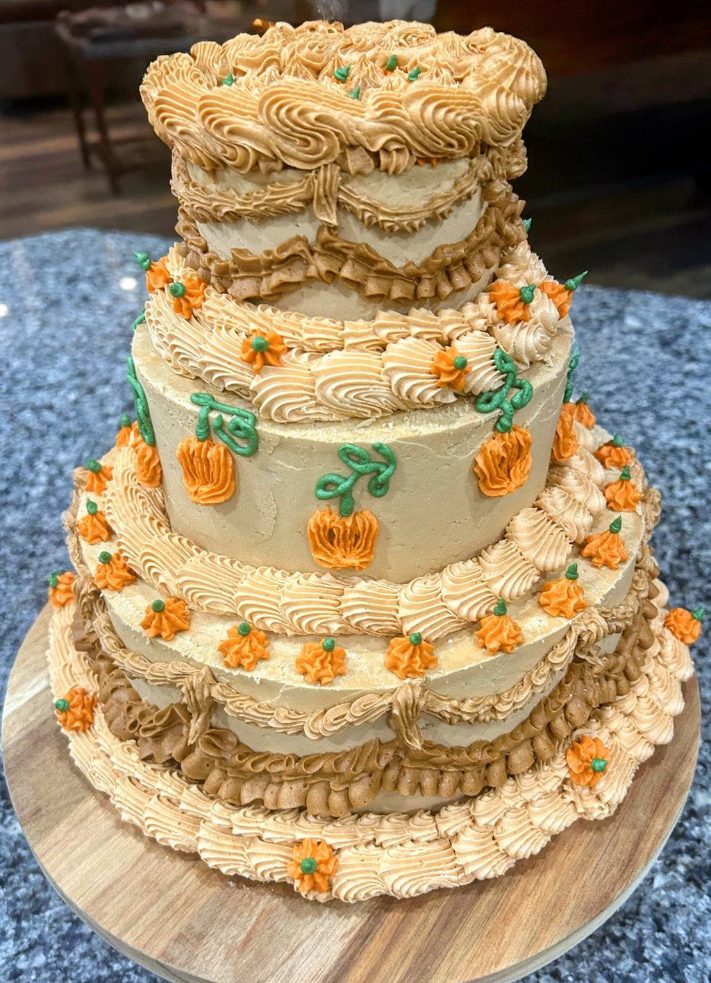 Three-tiered cake with decorative icing and pumpkins on a wooden cake stand.